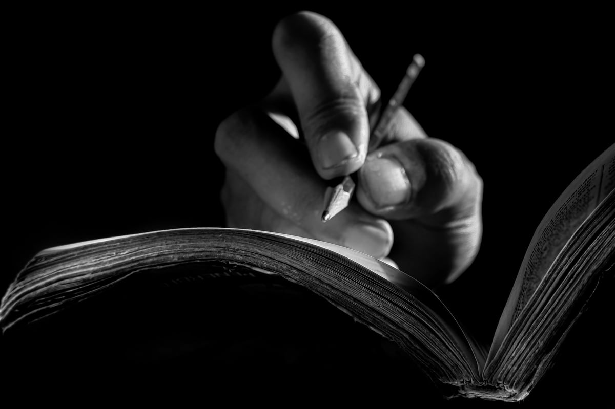 Close Up of Hand Writing with Pencil on Notebook